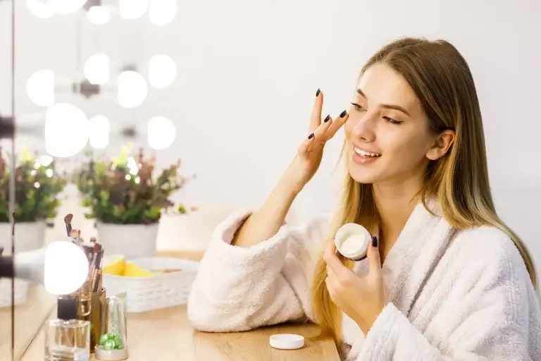 Femme appliquant une crème hydratante devant un miroir